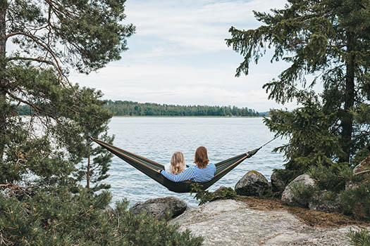 Two persons sitting on a hammock in front of the sea