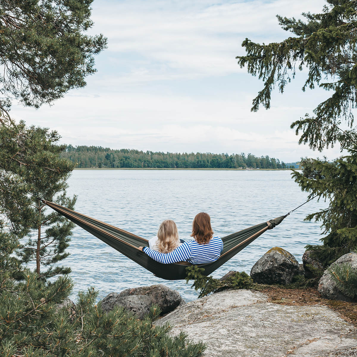 Two persons sitting on a hammock in front of the sea-big