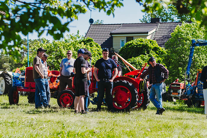 A group of men by an old tractor at Sommarstart celebration in Korpo