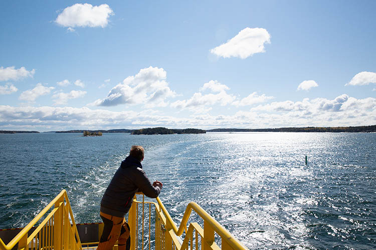 A person enjoying the view from the ferry on a beautiful sunny summer day in Korpo