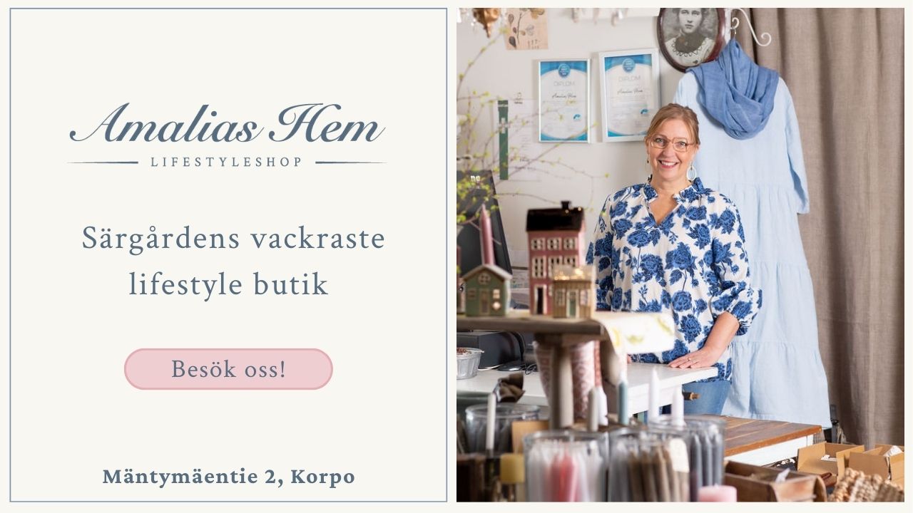 Reklambild för Amalias Hem livsstilsbutik som visar en leende kvinna som står inne i butiken omgiven av heminredningsartiklar; butiksinformation finns till vänster.