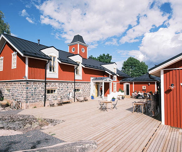 Hotel Nestorin päärakennus ja terassi Korppoossa aurinkoisena kesäpäivänä.