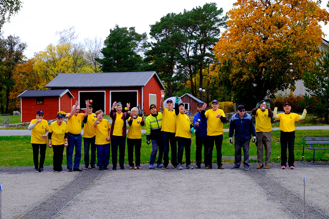 Ryhmä eläkeläisiä keltaisissa t-paidoissa pelaamassa petankkia Korpossa.