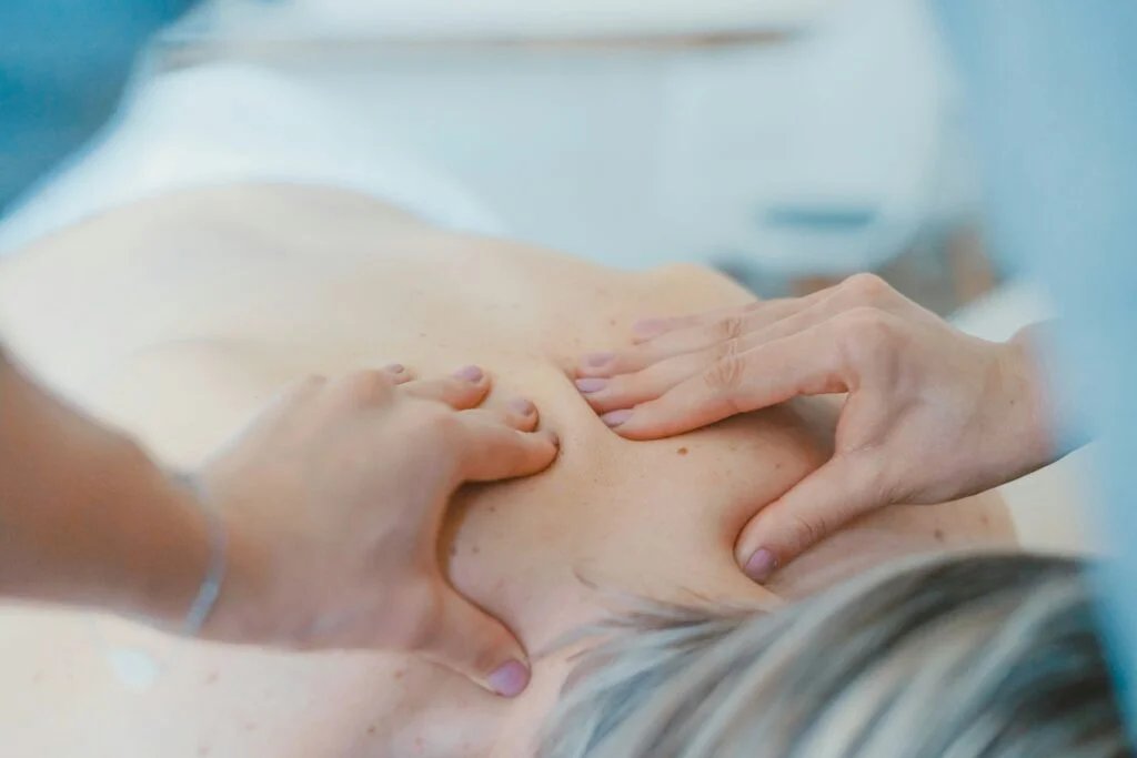 A therapist performs a back massage on a client in a spa environment.