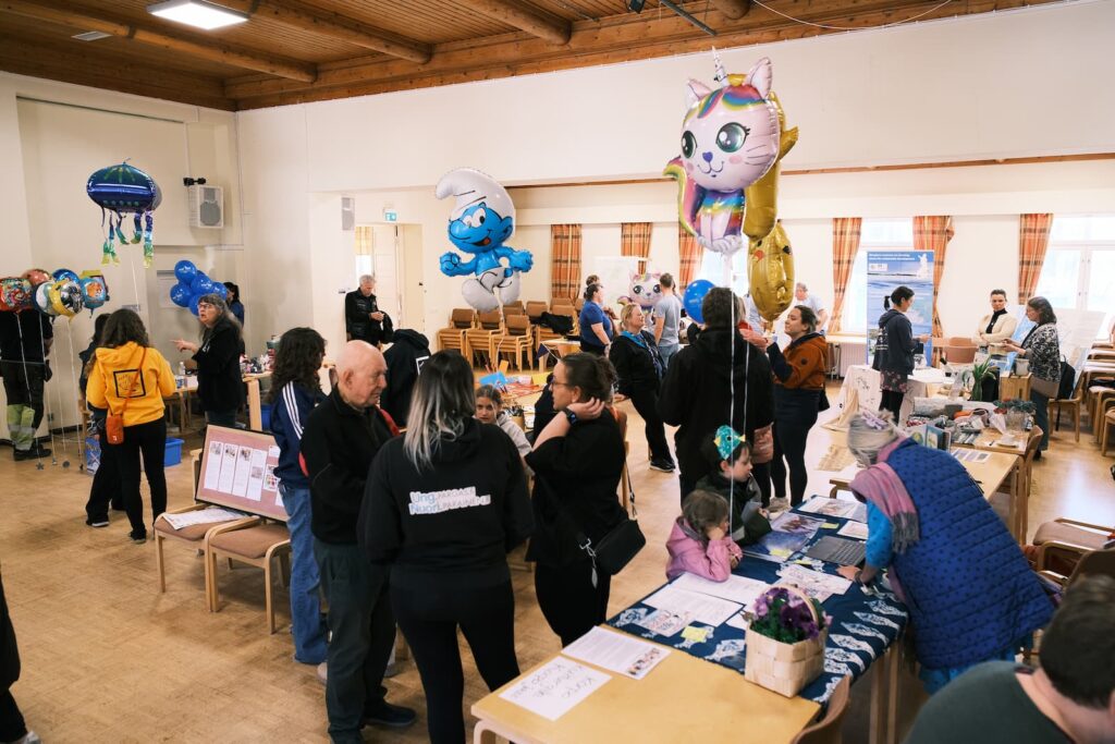 Inflyttningsjippo i Kommunalgården i Korpo, med människor, informationsbord och ballonger.